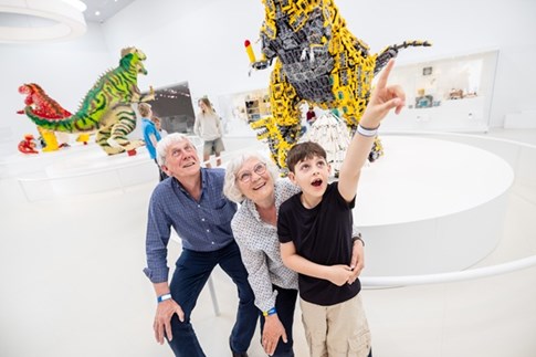 Eine Familie mit Großerltern vor Legodinosauriern