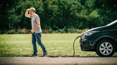 Mann sucht die Ladestation für E-Auto entlang der Urlaubsstrecke