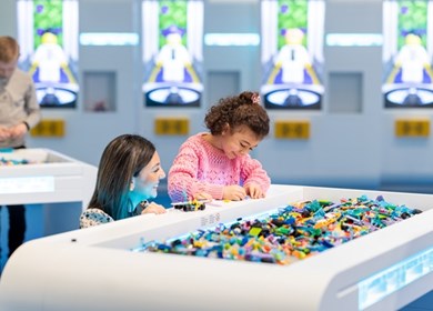 Kind spielt mit seiner Mutter am Legotisch